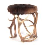 A FUR COVERED STAGHORN STOOL with circular-shaped top and intertwined horn supports 42cm diameter