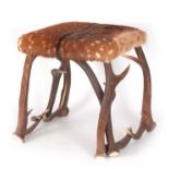 A FUR COVERED STAGHORN STOOL with square-shaped top and intertwined horn supports 44cm square 45cm