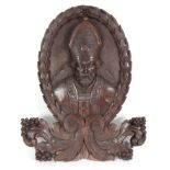 A 19TH CENTURY CARVED OAK WALL PLAQUE modelled as a bishop with garland frame above carved leaves