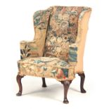 A GEORGE I MAHOGANY WINGBACK ARMCHAIR with shaped sides and scrolled arms, upholstered in