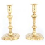 A PAIR OF 18TH CENTURY CAST BRASS CANDLESTICKS with shaped square bases, knopped tapering stems