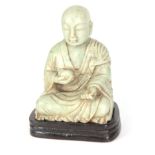 A CHINESE PALE GREEN JADE LARGE SCULPTURE OF A SEATED BUDDHA on a lacquered wood stand 22cm high