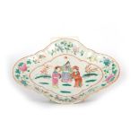 AN 18th CENTURY CHINESE DISH OF SHAPED FORM MOUNTED ON A PLINTH BASE brightly decorated with a