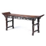A 19th CENTURY CHINESE HARDWOOD ALTAR TABLE with panelled top having shaped ends above a pierced