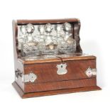 A 19TH CENTURY OAK AND SILVERED BRASS MOUNTED TANTALUS / GAMES BOX fitted three cut glass bottles