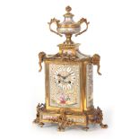 A LATE 19TH CENTURY FRENCH PORCELAIN AND ORMOLU MANTEL CLOCK the case surmounted by a large urn