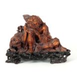 A FINELY CARVED WOOD CHINESE SEATED FIGURE OF AN ELDER depicted in a resting pose with dog of fo