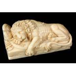 A 19TH CENTURY FINELY CARVED IVORY SCULPTURE DEPICTING A RECUMBENT LION sleeping on shields and
