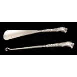 A CASED SILVER HANDLED BUTTON HOOK AND SHOE HORN on fluted leafwork and Tigers head handles set with