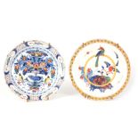 TWO EARLY 18TH CENTURY DELFT PLATES comprising one decorated with a bird perched on a yellow band