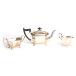 A GEORGE V SILVER THREE PIECE TEA SERVICE of plain angular form raised on cabriole feet teapot