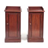 A PAIR OF LATE GEORGIAN FLAMED MAHOGANY BEDSIDE CABINETS with raised backs and hinged panelled