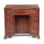 A 19TH CENTURY GEORGE III STYLE MAHOGANY SERPENTINE FRONTED KNEEHOLE DESK with one long and six