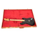 A BLACK FENDER STRATOCASTER ELECTRIC GUITAR serial number S971721, in a lined case.