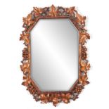 A LATE 19TH CENTURY BLACK FOREST LINDENWOOD MIRROR the rectangular frame with clipped corners carved