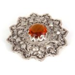 A SCOTTISH HIGHLANDS KILT SILVER BROOCH decorated with thistles surrounding an amber stone