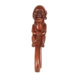 A 19TH CENTURY BLACK FOREST FRUITWOOD NUTCRACKER depicting a carved seated male figure 25.5cm high