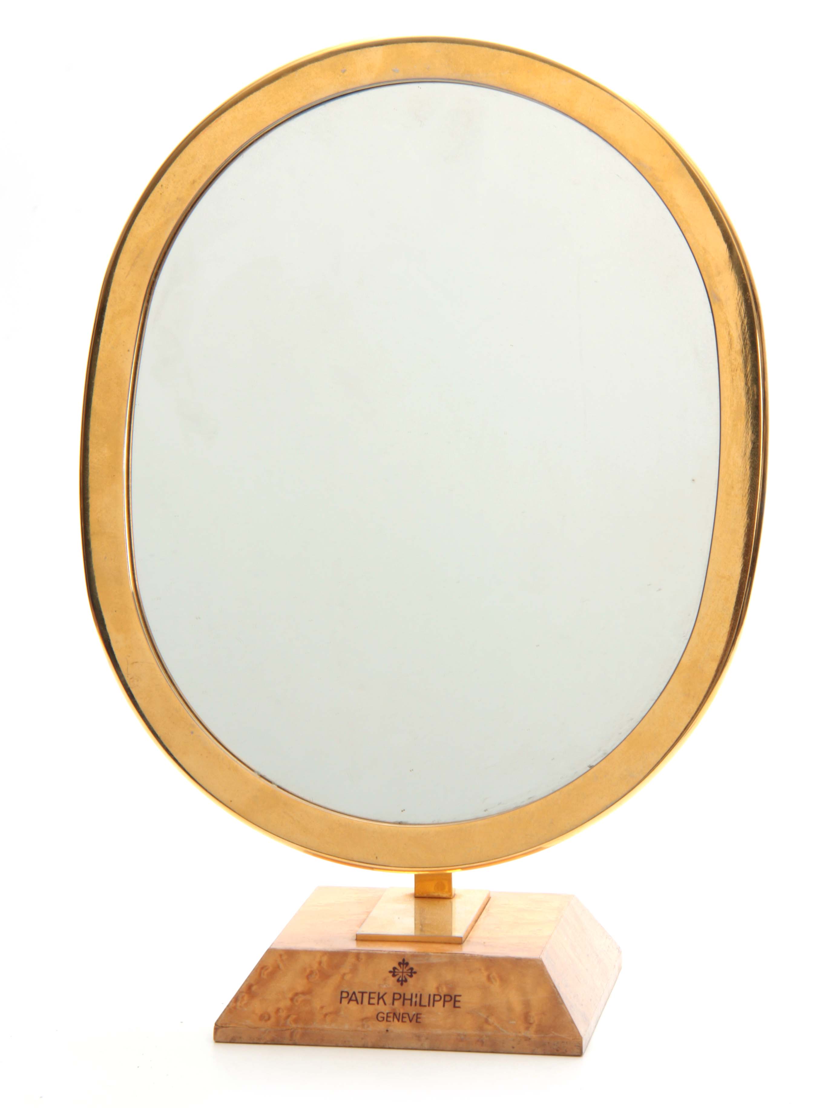 A VINTAGE PATEK PHILIPPE SHOP MIRROR the brass oval frame with pivoted adjustment mounted on a