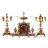 A 19TH CENTURY FRENCH EGYPTIAN STYLE ROUGE MARBLE AND ORMOLU MOUNTED CLOCK SET with stylised