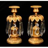 A PAIR OF REGENCY GILT BRASS CANDLESTICKS WITH PRISMATIC LUSTRE DROPS the leafwork dished circular