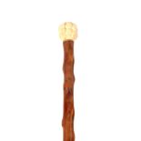 AN EARLY 20TH CENTURY CHINESE SWAGGER STICK WITH IVORY 1000 FACES POMMEL mounted on a knotted wood