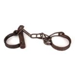 A 19TH CENTURY SET OF ANKLE CUFFS / SHACKLES fitted with the original key 50cm overall