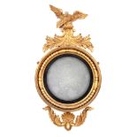 A REGENCY GILT GESSO CARVED CIRCULAR CONVEX HANGING MIRROR OF LARGE SIZE having an eagle and leaf