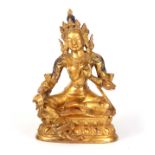 AN EARLY GILT BRONZE SCULPTURE OF THE BUDDHIST GODDESS TARA in a seated pose with blue stained