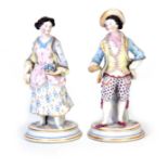 A PAIR OF LATE 19TH CENTURY COLOURED BISCUIT-WARE STANDING FIGURES each by a pillar finely dressed