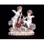 A CONTINENTAL PORCELAIN FIGURE GROUP modelled as two cherub musicians on a grape clad rocky oval