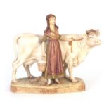 A ROYAL DUX BOHEMIA ANIMAL FIGURE modelled as a dairy cow and standing milk maid coloured in soft