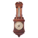A LATE 19TH CENTURY OVERSIZED ANEROID BAROMETER/THERMOMETER WITH ELABORATE CARVED WALNUT CASING