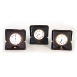 A COLLECTION OF THREE TRAVELLING CLOCKS in leather folding cases all with white enamel dials