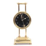 AN EARLY 20TH CENTURY BRASS GRAVITY CLOCK with glass dial with Arabic numerals fronting a gravity-