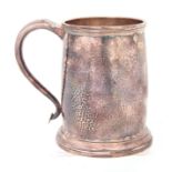 A GEORGE V SILVER PINT MUG of tapering footed hammered form with scroll handle 13cm high Sheffield