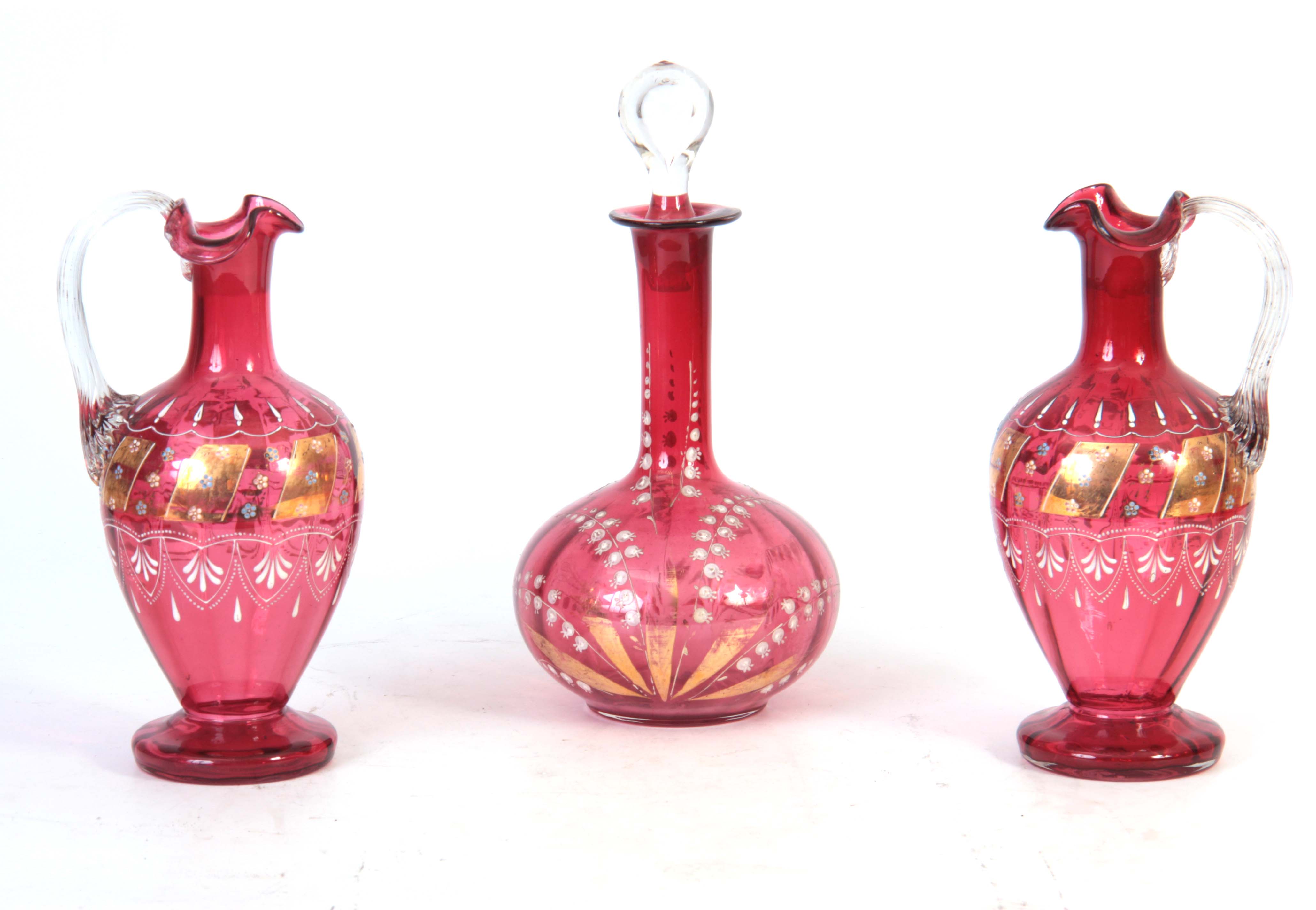 A PAIR OF VICTORIAN CRANBERRY DECANTERS with gilt panelled enamelled flower spray decoration to