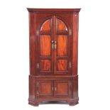 A GEORGE III MAHOGANY STANDING CORNER CUPBOARD with moulded dentil cornice above arched fielded