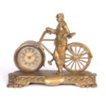 AN EARLY 20TH CENTURY BRASS NOVELTY MANTEL CLOCK formed as a gentleman stood beside a bicycle, the