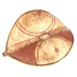 AN AFRICAN HIDE CHIEFTAIN'S SHIELD with bound stitched border and dark red painted decoration 74cm