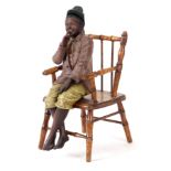 A LATE 19TH CENTURY PAINTED 'GOLDSCHEIDER' TYPE PLASTER MODEL of a young boy sat on a wood chair