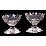 A PAIR OF GEORGIAN CUT GLASS TABLE SALTS the diamond-shaped stepped pedestal bases supporting oval
