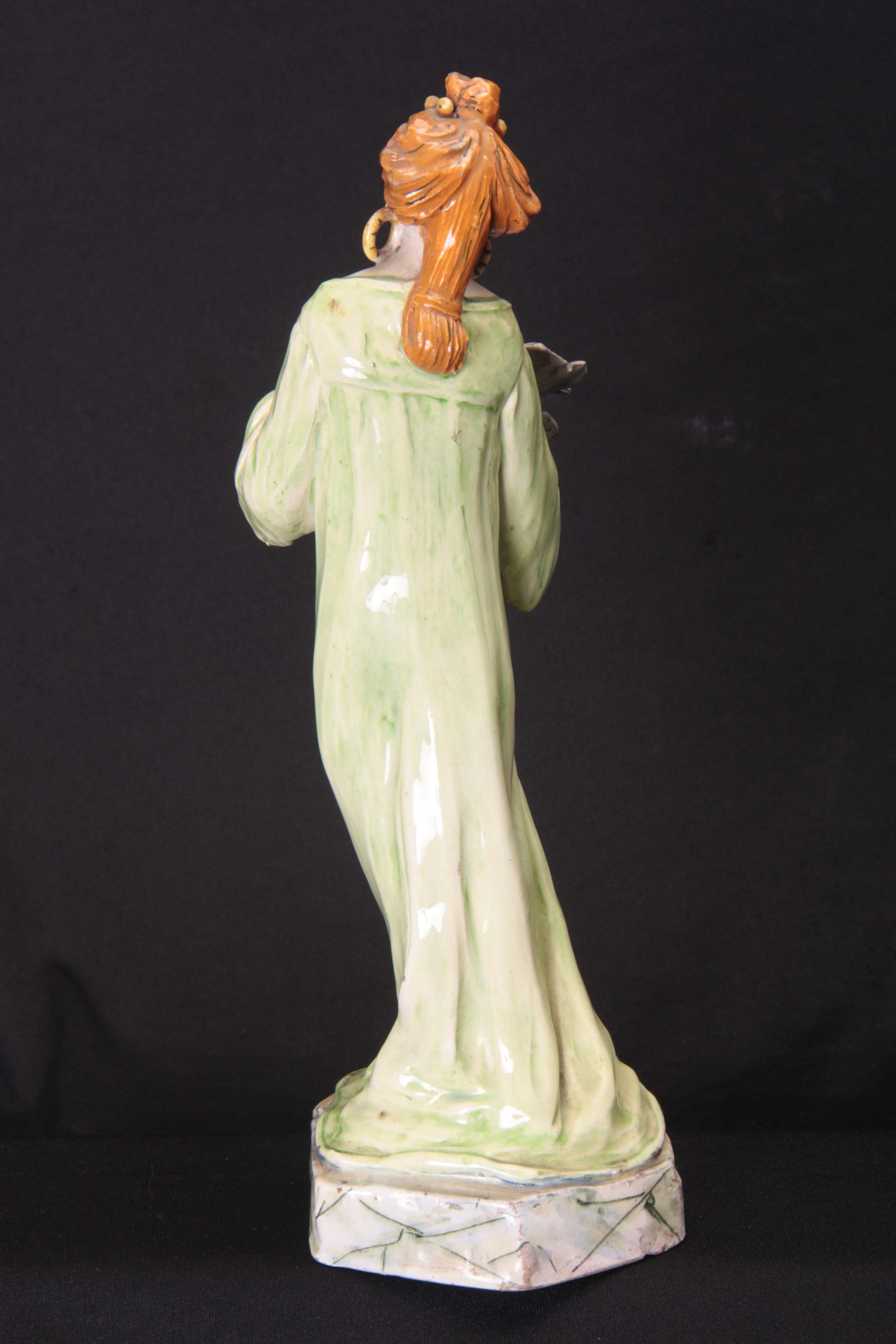 AN ART NOUVEAU GLAZED POTTERY FIGURE modelled as a standing lady clutching a flower head with hollow - Image 4 of 5