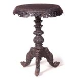 A 19TH CENTURY CARVED ANGLO INDIAN OCCASIONAL TABLE with circular carved top above a leaf carved