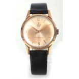 A GENTLEMANS VINTAGE 9CT GOLD TUDOR ROYAL WRIST WATCH on a black leather strap, the gold dial with