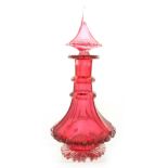 AN OVERSIZED BOHEMIAN RUBY GLASS DECANTER of faceted form with ringed neck and spire stopper 39cm