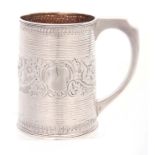 A GEORGE III SILVER MUG of ribbed tapering form with gilt interior with crested later embossed