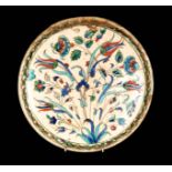 A LATE 16TH/17TH CENTURY ISNIK DISH decorated with brightly coloured floral work 31cm diameter (AF).