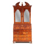 A WILLIAM AND MARY BURR WALNUT BUREAU BOOKCASE with broken arch pediment above shaped mirrored doors