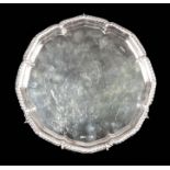 AN ELIZABETH II SILVER SALVER with plain centre and scalloped feather-edge border, on three scroll