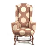 A LATE 19TH CENTURY QUEEN ANNE STYLE UPHOLSTERED WING BACK ARMCHAIR with shaped back and swept arms,